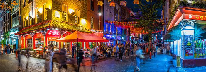 Crowds of people enjoying the warm summer night in the busy pedestrianised streets of Chinatown, London.