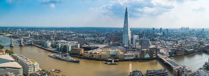 Aerial panorama over the River Thames towards Tower Bridge, the South Bank and the iconic spire of the The Shard, London, UK.