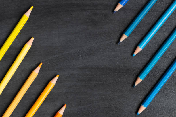 istock yellow and blue coloured pencils on a chalkboard 1333572088