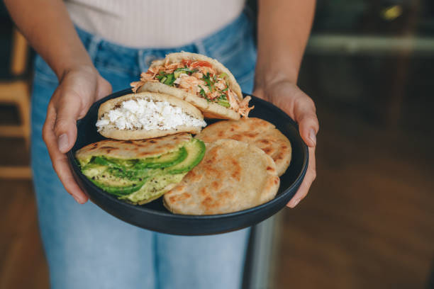 Woman holding a plate with arepas
