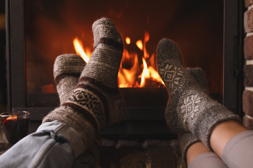 Couple resting near fireplace indoors, closeup. Winter vacation
