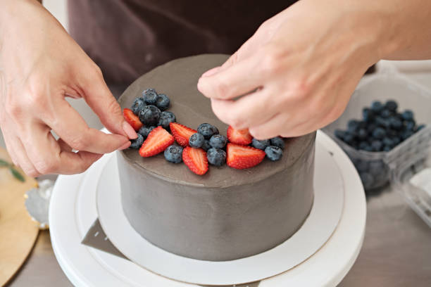 istock Woman pastry chef decorates grey cake with berries, close-up. Cake making process, Selective focus 1333575665