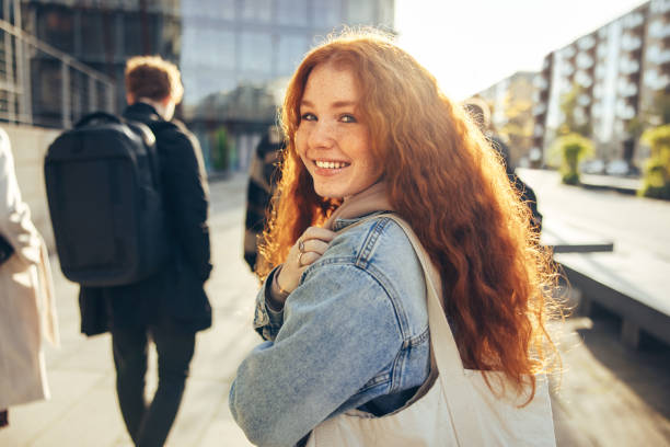 linda estudante andando e sorrindo de volta para a câmera - cabelo pintado de vermelho - fotografias e filmes do acervo