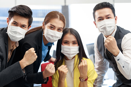 Group of young Asian business team with the mask on working together in the office. Office business people brainstorming in the meeting. Strat up business team discussing about new project.