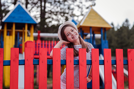 Smiling young girl at the colorful playground fence