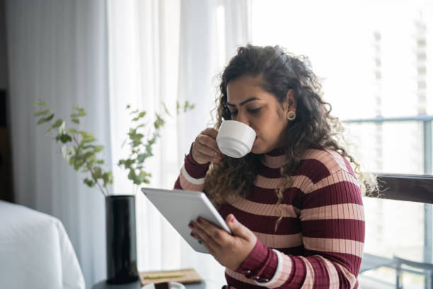 istock Woman drinking coffee and using digital tablet at home 1333590320