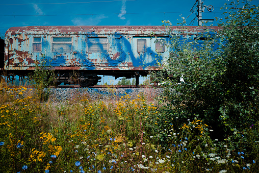 Color image depicting an old train carriage that has been abandoned on the railroad track and left to rust and ruin.