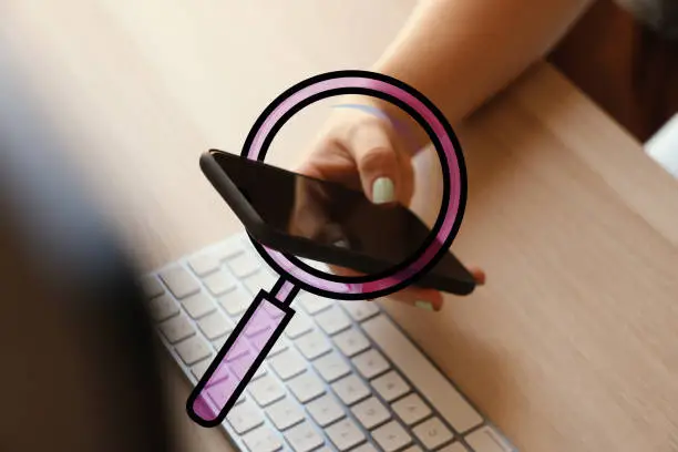 Photo of Woman holding mobile phone with magnification glass