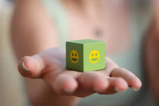 Photo of Women holding green wood block with smiley face