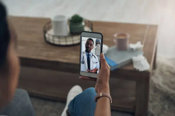 Photo of Shot of an unrecognizable person on a videocall with a doctor
