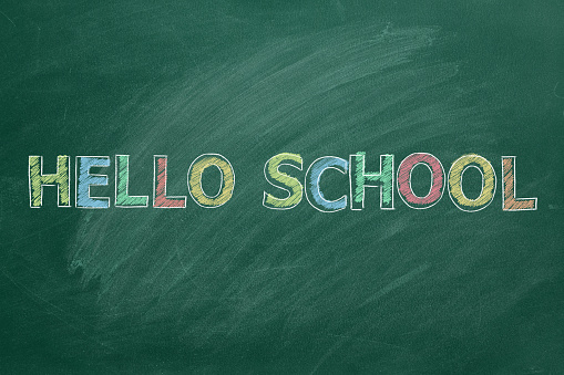 Hand drawn Hello School text on green chalkboard. Back to School concept