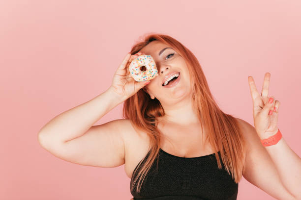 istock Joyful oversized young woman laughs holding dessert donut 1333602900