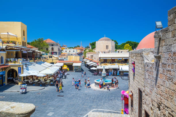 sightseeing place at hot summer sunshine afternoon. tourists at the intersection aristotle str""socrates str- hippocrates square at the rhodes old town of rhodes, greece - editorial built structure fountain town square imagens e fotografias de stock