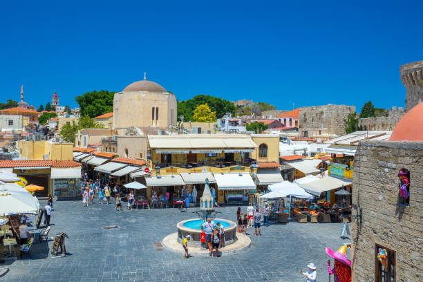 tourists at the intersection aristotle str""socrates str- hippocrates square at the rhodes old town of rhodes, greece - editorial built structure fountain town square imagens e fotografias de stock