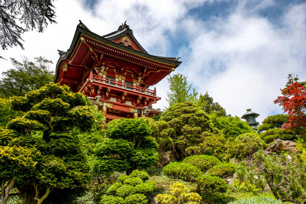 a gazebo at the edge of a pond surrounded by gardens and forest