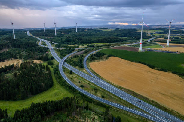 highway road interchange with wind turbines (aerial) aerial panoramic shot of the highway road interchange bridge crossing cloud built structure stock pictures, royalty-free photos & images