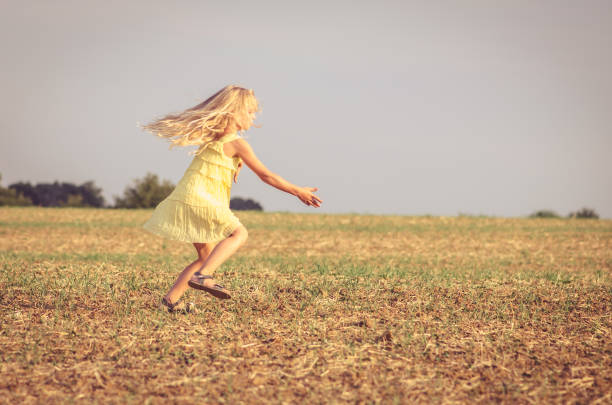 istock spontaneous child in yellow dress dancing wildly in rural path 1333611992