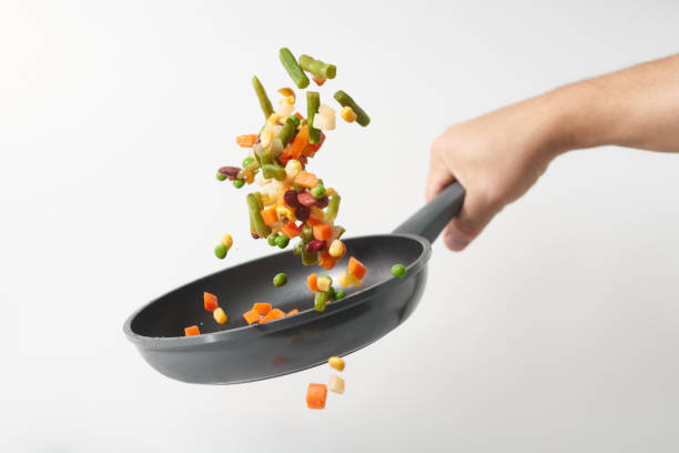 les légumes frais volent dans une casserole sur fond blanc. cuisson avec divers légumes hachés dans une casserole. le concept d’alimentation et d’alimentation saines. « n - poêle verte photos et images de collection