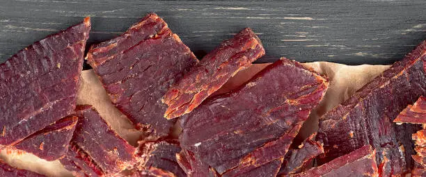 Close up view of beef jerky pieces on a wooden table, top view.
