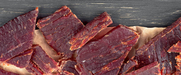 close up view of beef jerky pieces on a wooden table, top view. - beef jerky meat smoked imagens e fotografias de stock