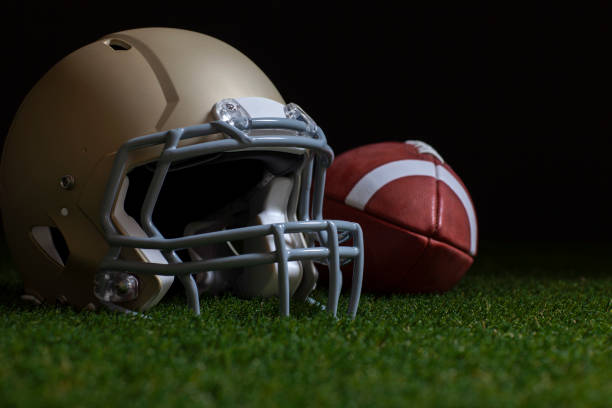 istock Low angle selective focus of football and gold helmet on grass with dark background 1333626607
