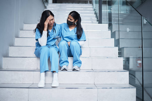 foto de una enfermera consolando a su colega mientras estaba sentada en una escalera en el trabajo - doctor tired protective workwear sadness fotografías e imágenes de stock