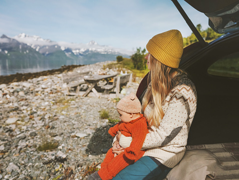 Mother with baby on road trip family travel vacation car camping woman with child enjoying mountains view in Norway