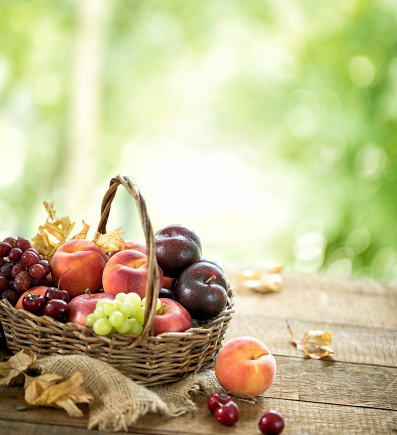 Basket with fresh ripe apples standing on a table, fruit harvest in the summer, healthy organic food