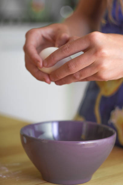 istock Preparing breakfast. A girl in an apron breaks eggs into a bowl. Hands close-up. Cooking. Vertical photo. 1333636894