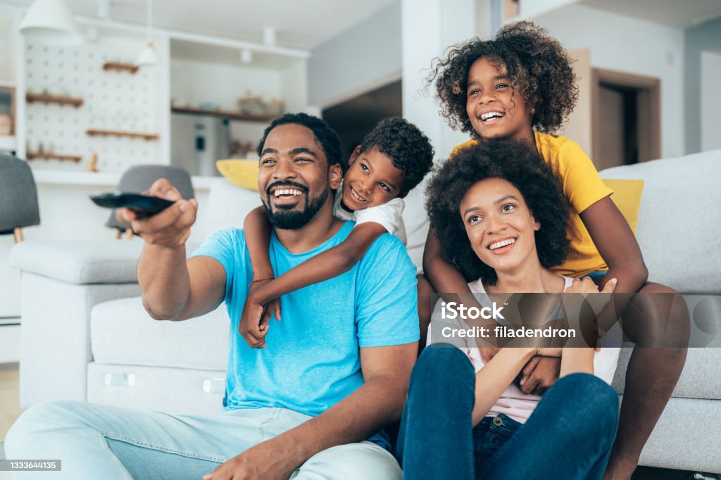 Family watching television Family relaxing at home watching television together Family Stock Photo