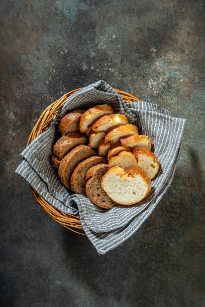 Slices of white bread with whole grain bread in a small wicker basket on colored background.