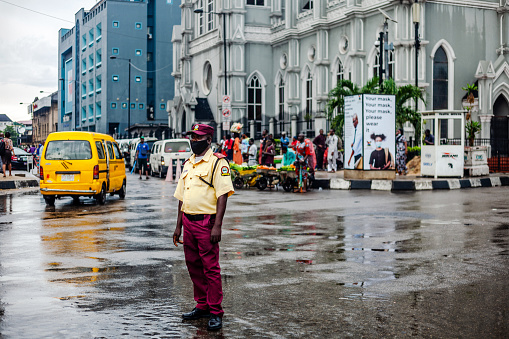 Lagos, Nigeria: Policeman standing in the middle of street - commuters and traffic in Lagos Island district.