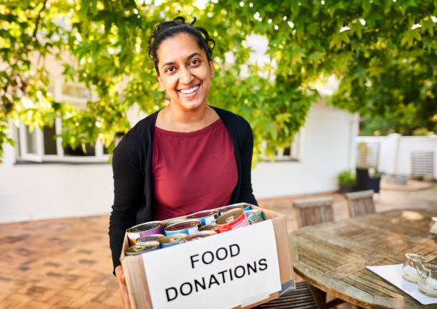 Woman with food donation box at a community center Happy woman with a box full of food donation packets at a community center community center food stock pictures, royalty-free photos & images