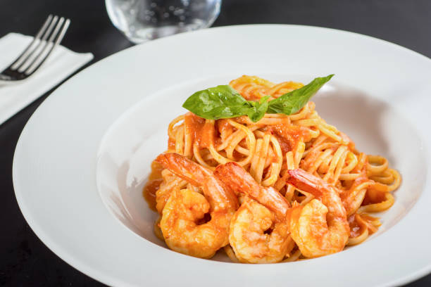 istock Pasta with jumbo shrimp on a white plate on a black background. 1333648101