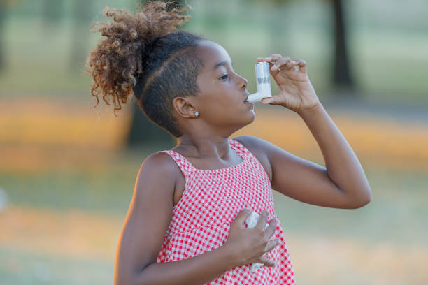 allergisches süßes kleines mädchen mit lockigem haar verwendet asthma-inhalator im park. - asthmatic child asthma inhaler inhaling stock-fotos und bilder