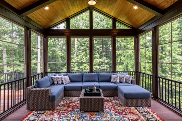 Newly Furnished Porch Enclosure New modern screened porch with patio furniture, summertime woods in the background. New home addition concept. porch stock pictures, royalty-free photos & images