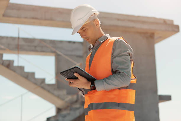 istock An engineer in an orange vest and white construction control helmet conducts an inspection with a tablet in his hands. 1333658831