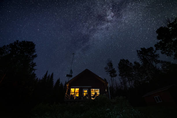 Night Sky and Milky Way Nature Panorama behind a beautiful tiny house or chalet in the forest