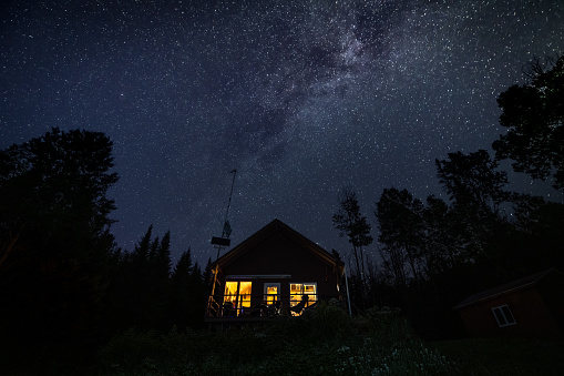 Night Sky and Milky Way Nature Panorama behind a beautiful tiny house or chalet in the forest
