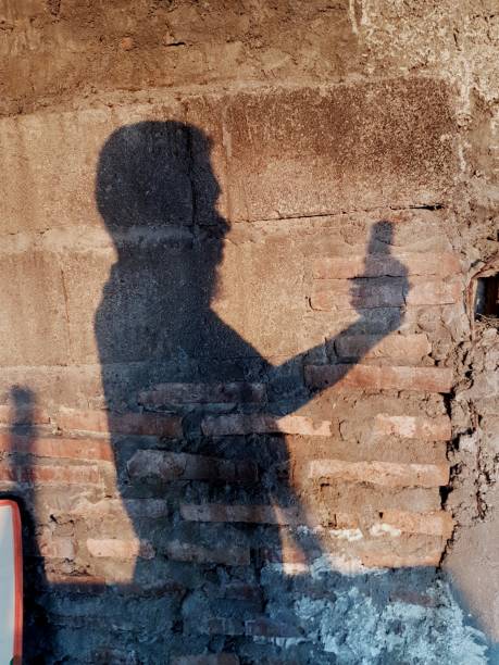 istock shadow of a man holding a cellphone on a worn red brick wall 1333671020