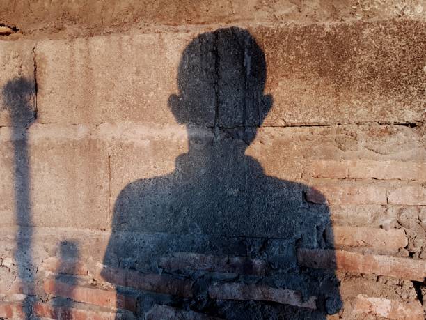 istock the shadow of a man on a worn red brick wall 1333671037