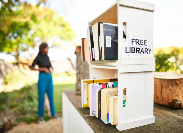 Little free street library outdoors Little free street library on a house front yard with a girls seen talking in background  free education stock pictures, royalty-free photos & images