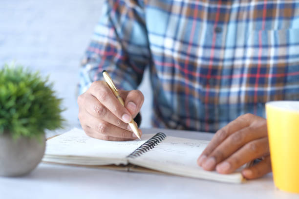 istock Close up of man hand writing on notepad. 1333674366
