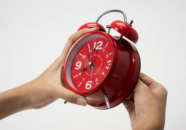 istock Female hand to match alarm clock 1333678836