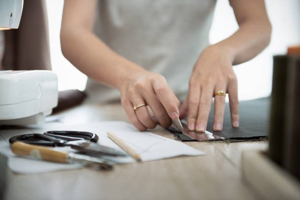 istock Close up hand of woman while draft patterns on fabric with tailor`s chalk for sewing. 1333685942