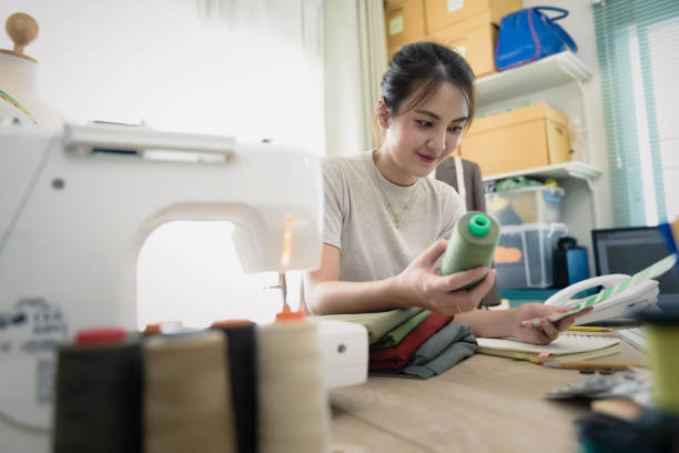istock Young female designer or tailor at works in design studio holding a cotton yarn while selection to colour tone for matching fabric material in design 1333685974