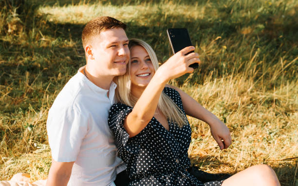 istock Smiling young couple makes a happy selfie on a mobile phone camera while camping, photo for memory or for social media. Beautiful love story, outdoor date. 1333687737