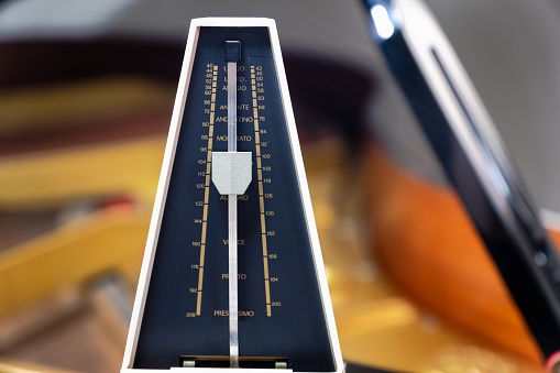 Metronome with pendulum to keep rhythm and tempo for piano, classical music, musicians - close-up with selective focus