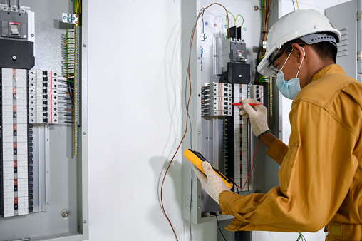Electrician engineer using digital multimeter test current electric in control panel \