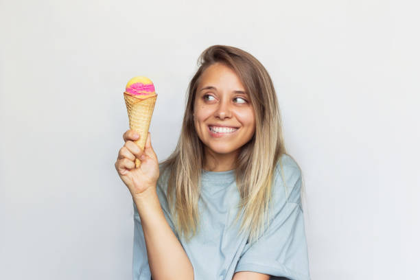 una giovane donna sorride guardando il gelato - cream horn foto e immagini stock